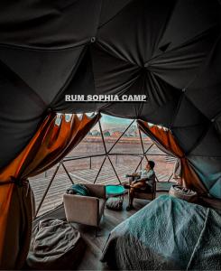 a man sitting in a chair under an umbrella at Rum Sophia camp in Wadi Rum