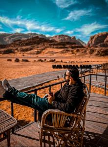 a man sitting on a bench in the desert at Rum Sophia camp in Wadi Rum