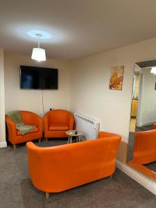 una sala de espera con sillas naranjas y TV de pantalla plana. en Orange Lilly In Stroud With Free Parking en Stroud