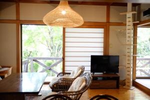 a living room with a table and chairs and a television at 'Imi Ola House in Yufuin