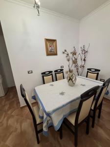 uma sala de jantar com uma mesa com cadeiras e um vaso sobre ela em Cobo Apartment's em Përmet