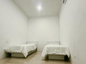 two beds in a room with white walls at LP Chamber Homestay Kota Marudu in Kampong Sorosob