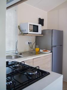 a kitchen with a microwave and a refrigerator at Camping Le Damier in Pianottoli-Caldarello