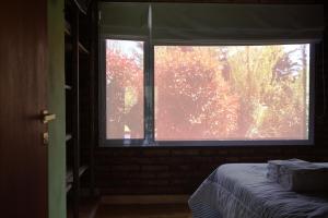 una ventana en una habitación con una cama delante en Cabañas El Rincón del Golf en Sierra de la Ventana