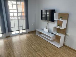 a living room with a television and white shelves at BALERMAPLAYA calle lago in Belerma