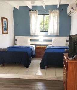 two beds in a room with blue walls and a tv at Bananaquit Near the beach! in Crown Point