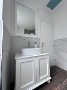 a white bathroom with a sink and a mirror at The Beach House in Birżebbuġa