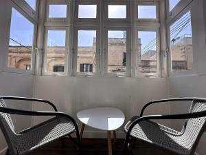 a table and chairs in a room with windows at The Beach House in Birżebbuġa