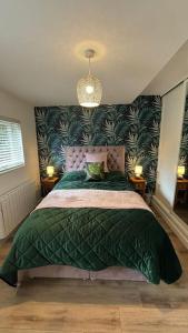 a bedroom with a large bed with a green blanket at Woodland Lodge, Llanteglos Estate in Narberth