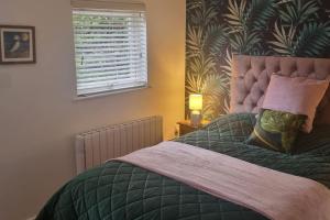 a bedroom with a bed with a green comforter and a window at Woodland Lodge, Llanteglos Estate in Narberth +8 photos