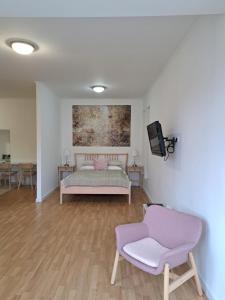 a bedroom with a bed and a tv and a chair at Gábriel apartman 3 in Kőszeg