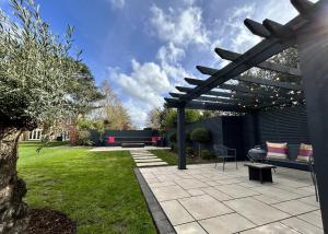 un patio avec une pergola et un banc dans une cour dans l'établissement Ascot Lodge, à Ibstock