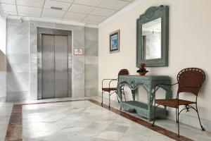 a hallway with chairs and a table and a mirror at Hotel Don Ignacio in San José
