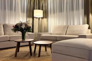 a living room with couches and tables with flowers at Hotel Don Ignacio in San José