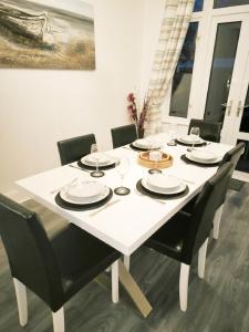 un tavolo bianco con sedie nere e una sala da pranzo bianca di 3 Bedrooms, Families, Contractors, Wi-Fi, Parking, Sleeps 7 - CLARK PROPERTY ESTATES a Southend-on-Sea