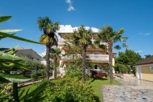a large building with palm trees in front of it at Apartments Šerbečić in Malinska
