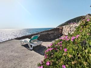 a chair sitting on the beach next to the water at Apartmani Seaside in Dobra Voda