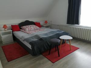a bedroom with a bed with red pillows and two tables at Betti Vendégház in Alsópáhok
