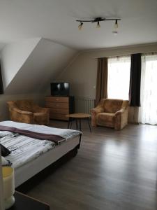 a bedroom with a bed and a tv and chairs at Betti Vendégház in Alsópáhok