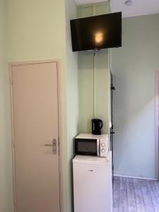Un four micro-ondes est installé au-dessus d'un réfrigérateur. dans l'établissement Résidences saint pierre, à Lourdes