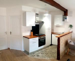 eine Küche mit weißen Schränken und einem Herd in der Unterkunft Vacances en famille 4 étoiles à 30min des pistes de Ski Mont Dore Sancy in Messeix