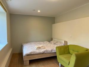 a bedroom with a bed and a green chair at Jaama Villa Studio Flat Surrounded by Garden in Tartu