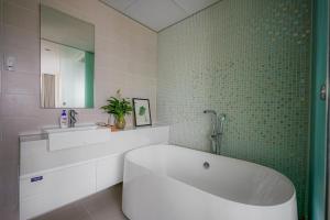 a bathroom with a tub and a green tiled wall at City By Night Ben Thanh Apartments in Ho Chi Minh City
