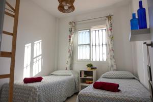 2 camas en un dormitorio con 2 ventanas en Tarifa Family House 5 min walk to the beach and old town en Tarifa