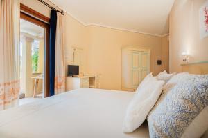 a bedroom with a large white bed and a window at Hotel Lu Pitrali in San Teodoro