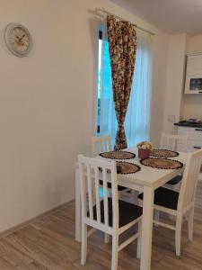 a white dining room table with chairs and a clock at Ayan Panoramic Baile Felix in Baile Felix