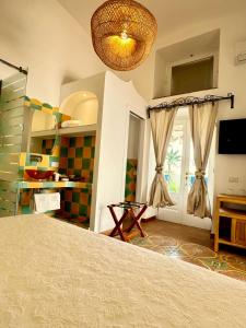 Cette chambre comprend un lit, une télévision et une fenêtre. dans l'établissement Villa Mary Suites, à Positano