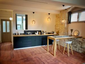 a kitchen with blue cabinets and a table with stools at La Maison de Margaret in Cluny