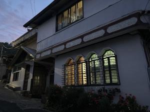 um edifício branco com janelas do lado em By the Old Swing em Baguio