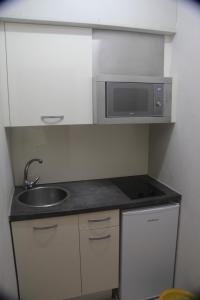 a small kitchen with a sink and a microwave at Aparthotel Els Molins in Roses