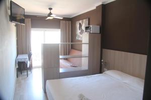 a small bedroom with a bed and a tv at Aparthotel Els Molins in Roses