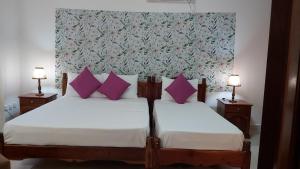 um quarto com 2 camas e almofadas roxas em Emma's Guest House and Self-Catering em Au Cap