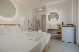 - une chambre blanche avec un lit et des serviettes dans l'établissement Golden Bird's, à Naxos Chora