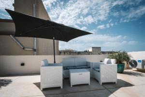 a patio with a table and chairs and an umbrella at Dar Barbara- Studio Apartments with Roof terrace in Cospicua