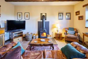 un salon avec un canapé et une cheminée dans l'établissement Romantic Country Cottage with log burner, garden patio, outdoor tub and country views- Brecon Beacons National Park, à Llangadog