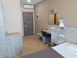 1 dormitorio con escritorio, 1 cama y espejo en The Santo George Beach Resort, en Amoudara Herakliou