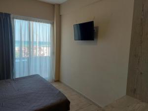 um quarto com uma cama e uma televisão na parede em The Santo George Beach Resort em Amoudara Herakliou