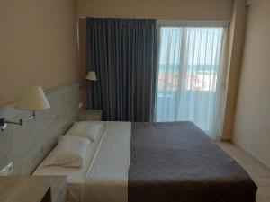 um quarto com uma cama grande e uma janela em The Santo George Beach Resort em Amoudara Herakliou