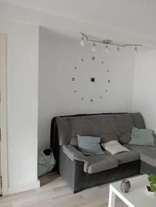 a couch in a living room with a clock on the wall at Alojamiento cerca de la Playa in Valencia