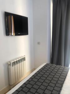 a bedroom with a bed and a tv on the wall at Habitacion con baño privado in Madrid