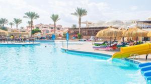 uma piscina num resort com palmeiras e guarda-sóis em Protels Beach Club & SPA em Marsa Alam