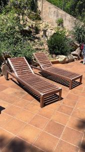 2 bancos de madera sentados en un patio de ladrillo en Villa in Tossa de Mar (Santa María de Llorell), en Tossa de Mar