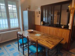 une cuisine avec une table en bois avec des chaises et un réfrigérateur dans l'établissement Chez Dom et Pascal, à Plestin-les-Grèves