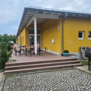 a yellow house with a table and chairs on a patio at Apartment number 2 in Oberschleißheim +7 photos