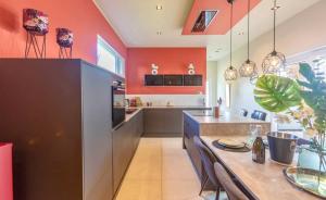 uma cozinha com paredes cor de laranja e uma mesa com cadeiras em Maison de vacances em Dalhem