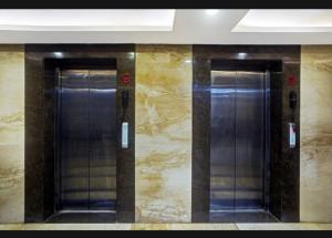 2 puertas de ascensor en un edificio con paredes de mármol en Hotel Vinnie, en Jaipur